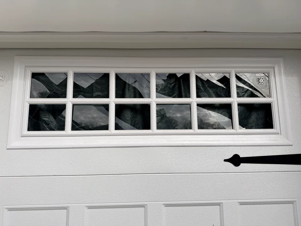 A garage door window insert with cracked and shattered panes