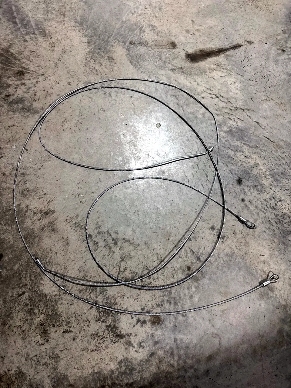 Two loose garage door lift cables lying on a concrete garage floor