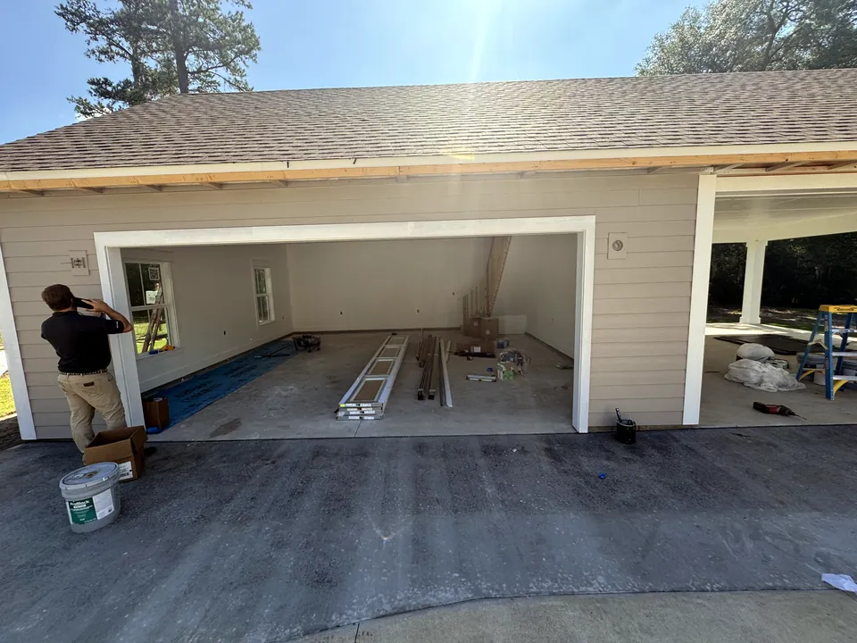 An open garage bay on a newly built house, with garage door sections and track laid out on the floor